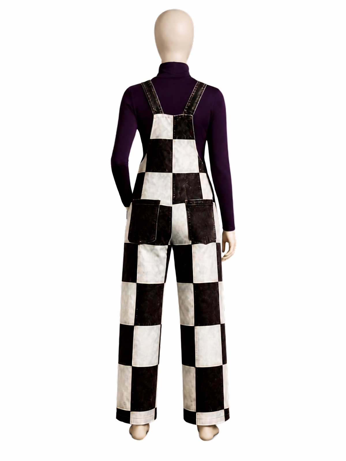 A mannequin wearing a black and white checkered patchwork overall jumpsuit over a dark purple long-sleeve turtleneck, shown from the back against a plain white background.
