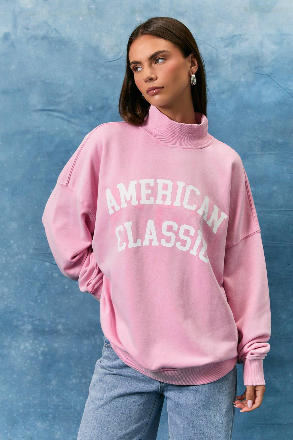 Person wearing a pink sweatshirt with 'American Classic' text against a blue textured background