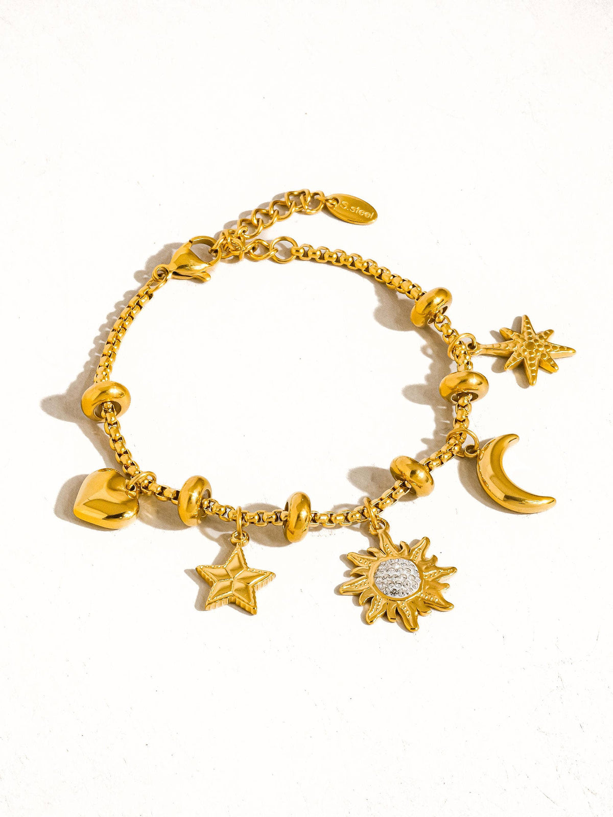 Gold bracelet with various charms on a white background