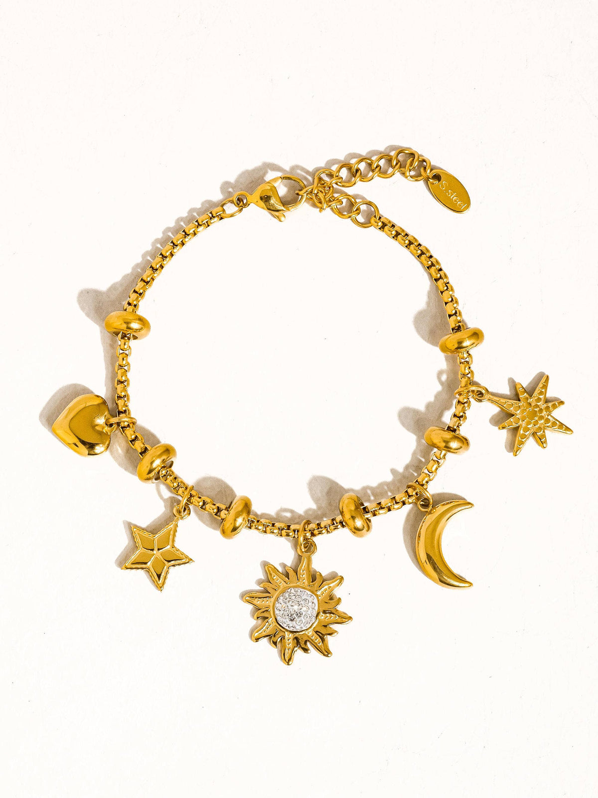 Gold bracelet with star, moon, and sun charms on a white background