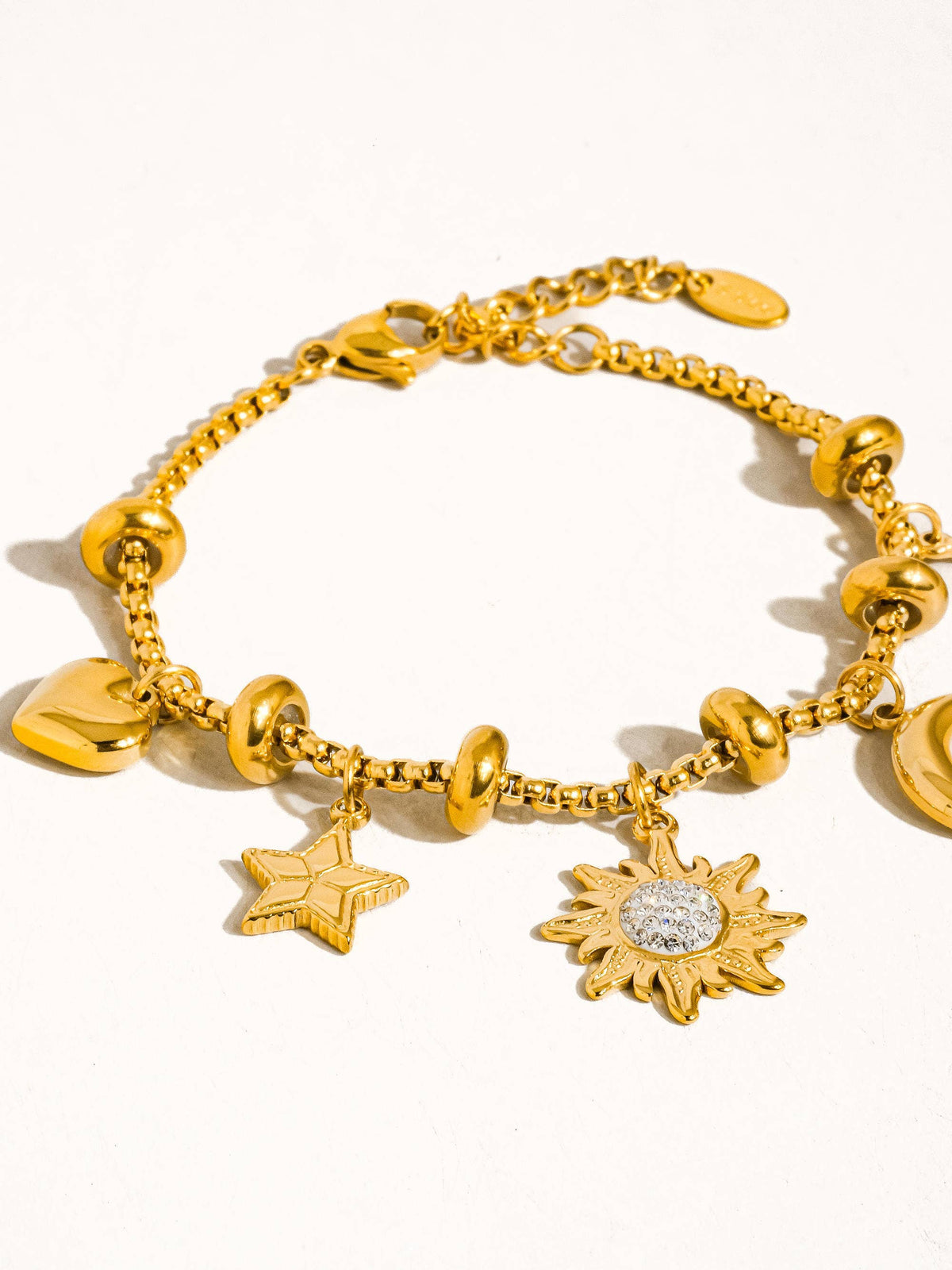 Gold bracelet with various charms on a white background